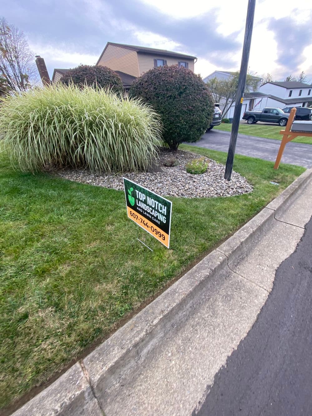 Landscaping sign for Top Notch Landscaping services in a residential yard.
