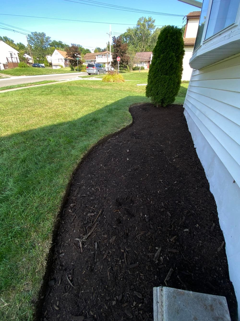 Landscape with fresh mulch and manicured grass along a home’s foundation.